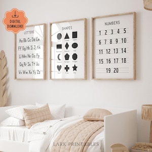 May include: Three framed educational prints with a neutral color palette. The prints display letters, shapes, and numbers 1-20 in a clean, minimalist style. The frames are light wood, and the prints are displayed above a bed with neutral bedding.