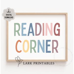 Puede incluir: Una impresión enmarcada con las palabras "READING CORNER" en letras de bloque coloridas. La impresión está en un marco de madera clara y presenta un icono de descarga digital en la esquina superior izquierda. El texto "LARK PRINTABLES" está en la parte inferior.