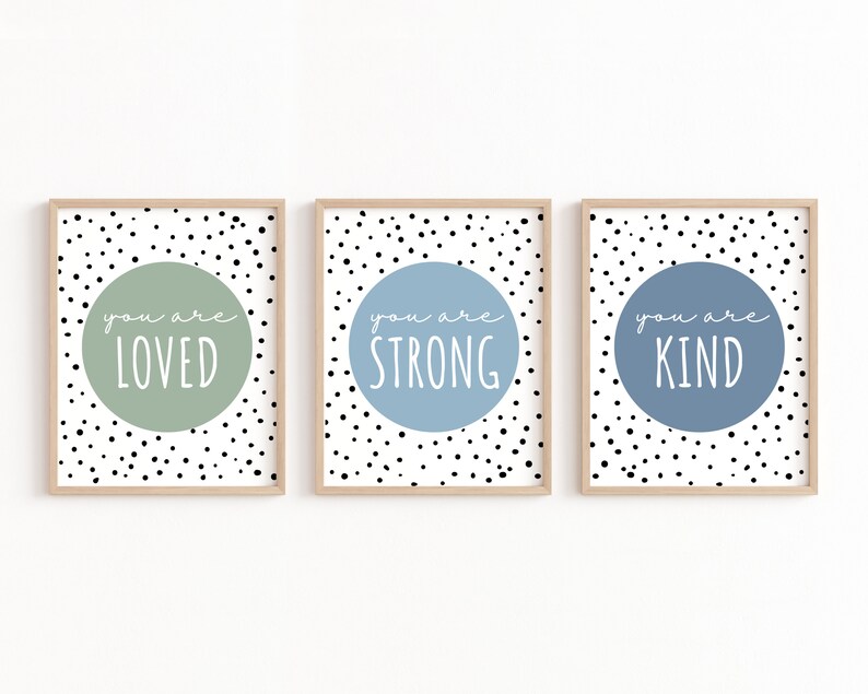 May include: Three framed prints with black and white polka dot backgrounds. Each print features a light blue or green circle with white text that reads "you are loved", "you are strong", and "you are kind".