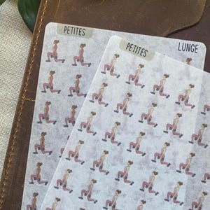 Könnte beinhalten: Zwei Stickerbögen mit Illustrationen einer Person, die Ausfallschritte mit Kurzhanteln ausführt. Die Sticker befinden sich auf einem durchscheinenden Hintergrund, auf dem das Wort "PETITES" auf einer der Bögen steht. Die Sticker liegen auf einem braunen Leder-Notizbuch.