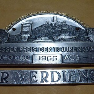 May include: A silver and gold metal badge with the text "Grosser Preis Der Tourenwagen Nürburgring 1966 ACS - ADAC" and "Für Verdienste".