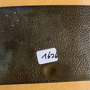 May include: A rectangular, bronze-coloured metal plate with a textured, hammered surface. The plate has two holes and a sticker with the number "1626" written on it. The text "S.W. REED & CO. WORCESTER" is visible.