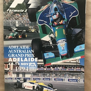 May include: A vintage Formula 1 racing program cover showing a green and blue Benetton race car. The cover displays the text "Adelaide Australian Grand Prix Adelaide 1994" and the Formula 1 logo. A collectible item for motorsport fans.