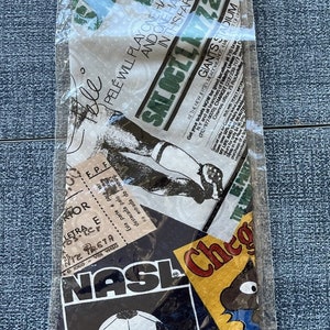 May include: A black and white tie with a collage of images, including a soccer ball, a newspaper clipping with the text "Pelé will play one half for Cosmos and one half for Santos in this farewell match", and the text "NASL".