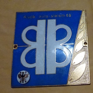 Puede incluir: Una insignia de esmalte azul y blanco con las letras "BB" en blanco sobre un fondo azul. La insignia tiene un borde dorado y un emblema de águila dorado en la esquina inferior izquierda. El texto "4.vcb auto-slalom 68" está impreso en blanco en la parte superior de la insignia.