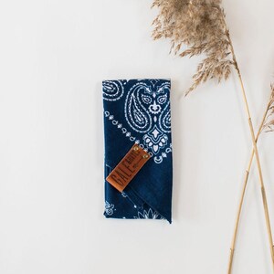 May include: A blue bandana with a white paisley pattern and a brown leather tag that says "GALE EARTH".