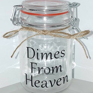 May include: A clear glass jar with a hinged lid and a red rubber seal. The jar is tied with twine and features the words "Dimes From Heaven" in black lettering. A decorative storage container.