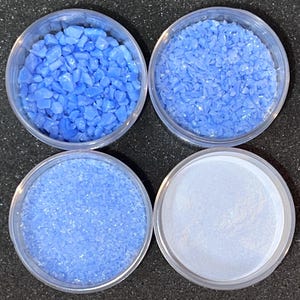 May include: Four small clear containers filled with different sizes of light blue glass glitter. The glitter is in various shapes and sizes.