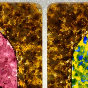 May include: Two square glass panels with a brown, speckled background. The left panel has a pink, bubbled design and the right panel has a yellow, green, and blue bubbled design.