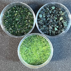 May include: Three small glass jars filled with different sizes of green glass pieces. The glass pieces are in various shades of green.