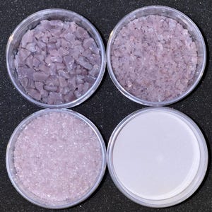 May include: Four clear plastic containers with lids, each containing a different size and shape of iridescent purple glass beads.