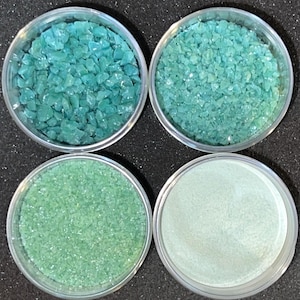 May include: Four clear plastic containers with lids, each filled with different sizes of turquoise green glass pieces. The containers are arranged in a 2x2 grid.