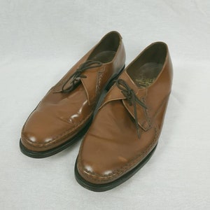May include: A pair of brown leather lace-up shoes with a pointed toe and a stitched detail around the edge.