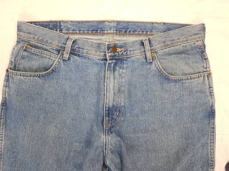 May include: A pair of blue denim jeans with a classic five-pocket style. The jeans have a light wash and a straight leg.