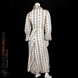 May include: A white maxi dress with a floral print and blue and white stripes. The dress has a high neck and long sleeves with ruffles at the cuffs.