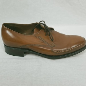 May include: Brown leather lace-up dress shoes with a stitched detail around the toe and a black rubber sole.