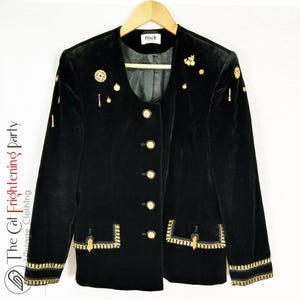 May include: Black velvet blazer with gold trim and buttons. The blazer has a round neckline and is adorned with gold embellishments.
