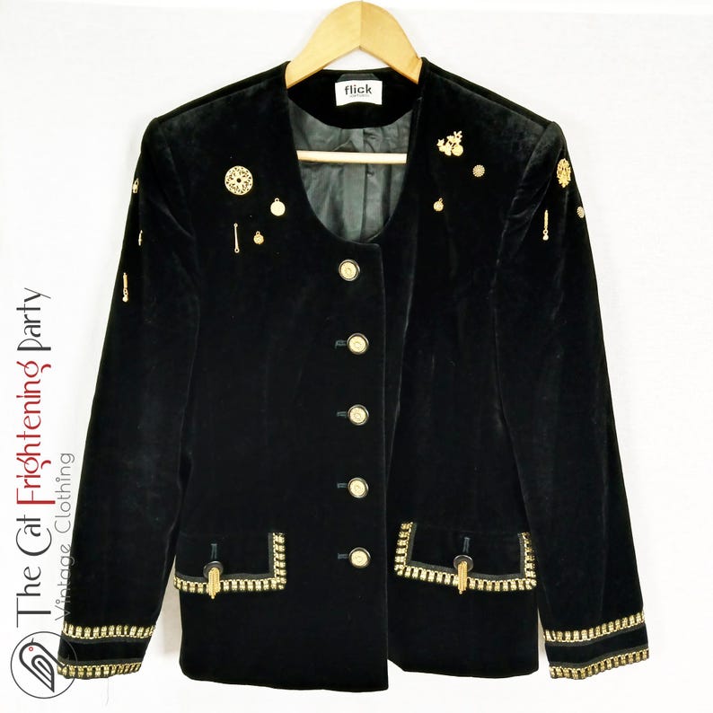 May include: Black velvet blazer with gold trim and buttons. The blazer has a round neckline and is adorned with gold embellishments.