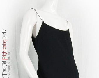 May include: A black sleeveless dress with thin straps. The dress is made of a smooth, silky fabric.
