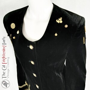May include: Black velvet blazer with gold-tone embellishments. The blazer has a scoop neckline and a button-up front.