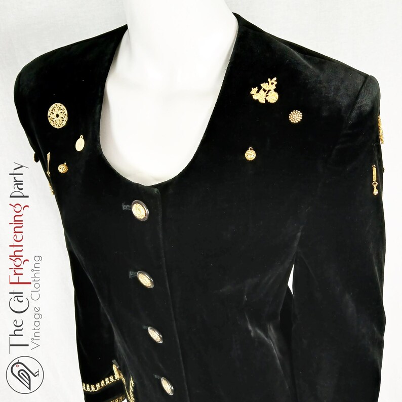 May include: Black velvet blazer with gold-tone embellishments. The blazer has a scoop neckline and a button-up front.