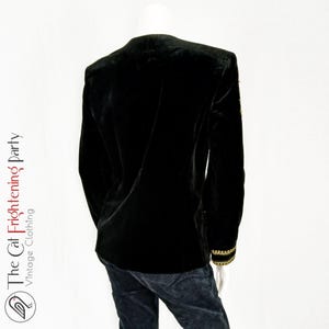 May include: Black velvet blazer with gold trim on the sleeves. The blazer has a classic cut and a tailored fit.
