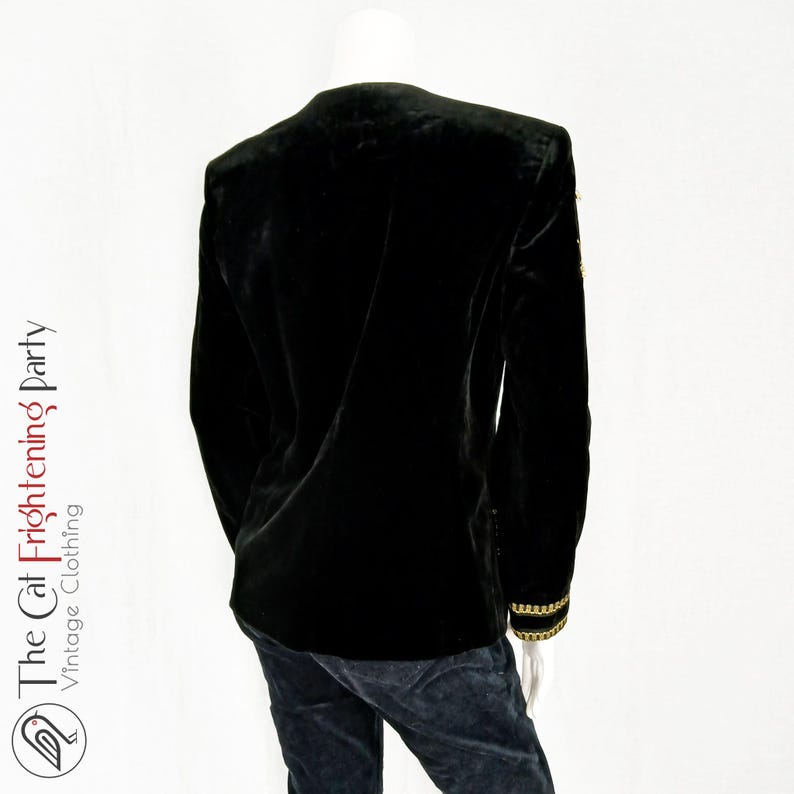 May include: Black velvet blazer with gold trim on the sleeves. The blazer has a classic cut and a tailored fit.