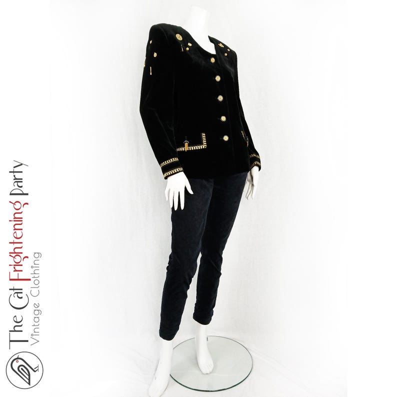 May include: A black velvet blazer with gold buttons and trim. The blazer has a classic style with a notched collar and long sleeves.