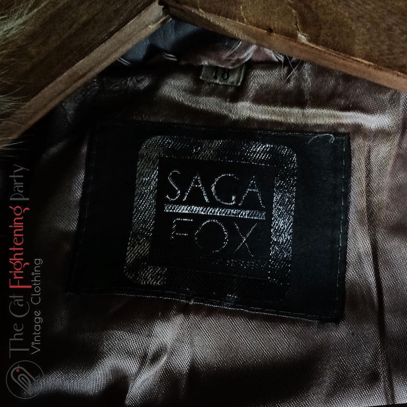 Op de afbeelding: Close-up van een zwart leren label met witte tekst die "SAGA FOX" luidt.