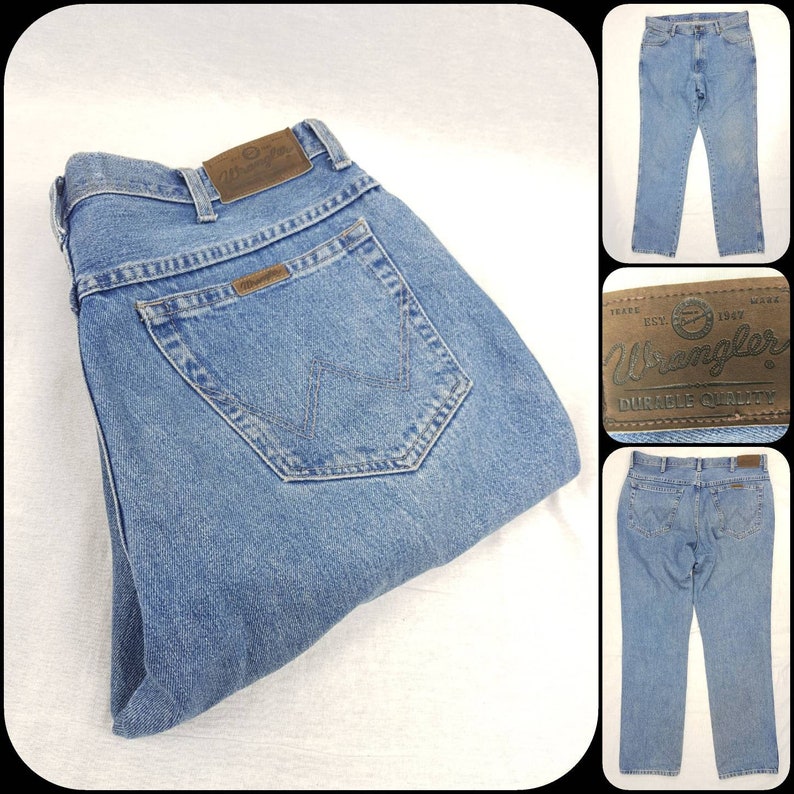 May include: A pair of blue denim jeans with a brown leather Wrangler label. The label has the Wrangler logo and the text "Wrangler Durable Quality".