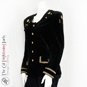 May include: A black velvet blazer with gold buttons and trim. The blazer has a stand-up collar and long sleeves.