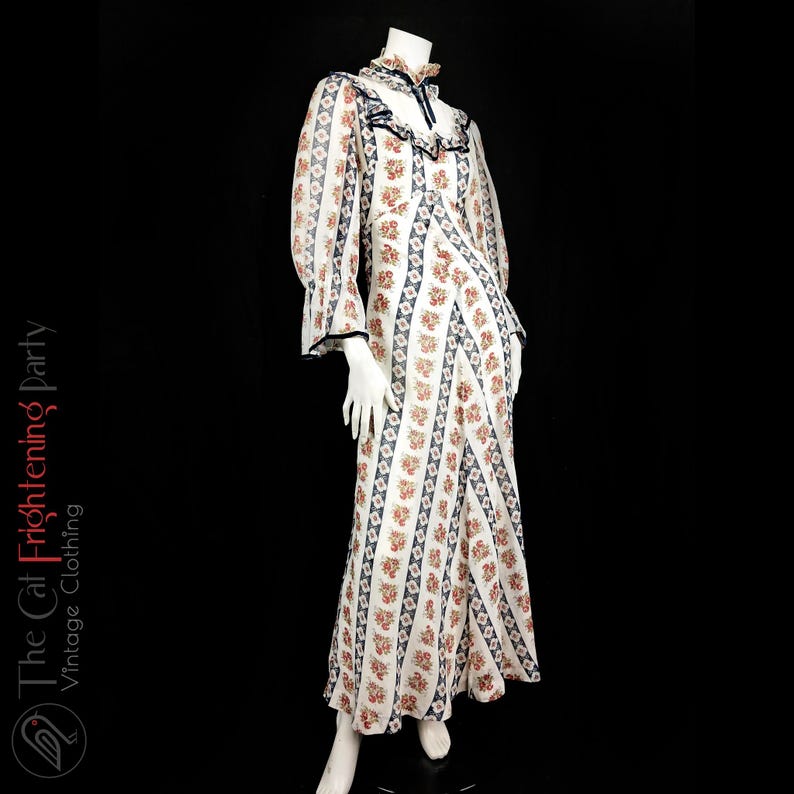 May include: A white maxi dress with a floral print and blue stripes. The dress has long sleeves with bell cuffs and a ruffled neckline.