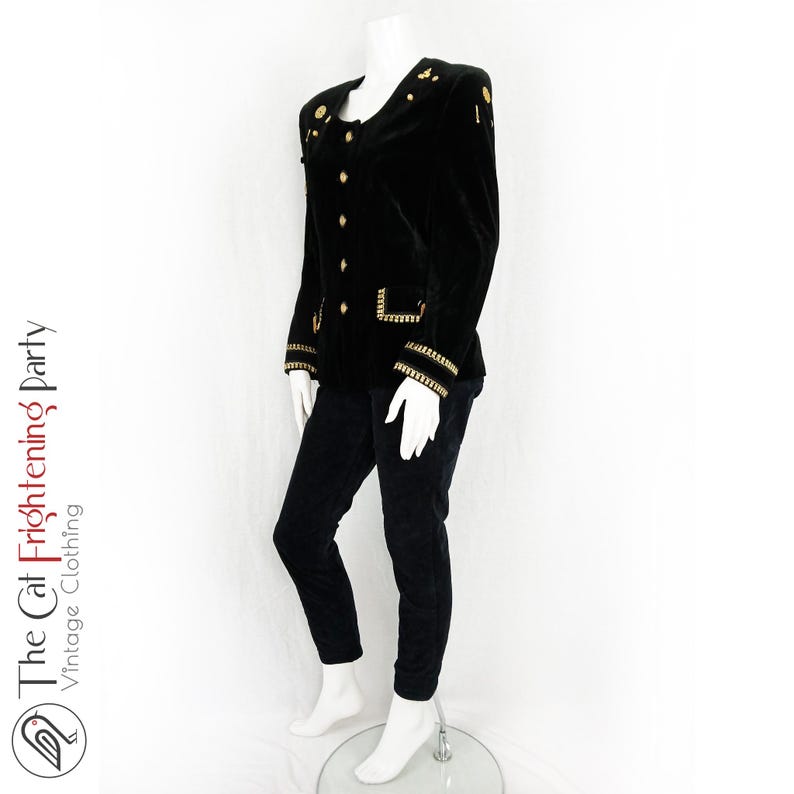 May include: A black velvet blazer with gold trim and buttons. The blazer has a stand-up collar and long sleeves.