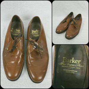 May include: A pair of brown leather lace-up shoes with a black sole. The shoes have a gold label on the inside that reads "Barker Fine English Shoes Established 1880 Northampton England."