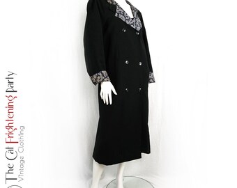 May include: Black vintage coat with a double-breasted design. The coat features a patterned collar and cuffs with a mix of tan, gray, and black. The coat is displayed on a mannequin.