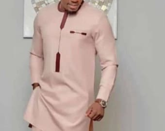 May include: A man wearing a light pink long-sleeved shirt and matching pants. The shirt has a maroon trim and a small pocket on the chest. The man is wearing sunglasses and a watch.