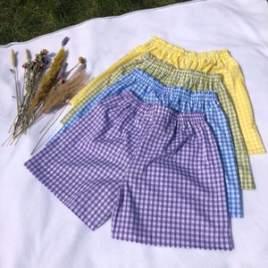 Può includere: Quattro paia di pantaloncini a quadri in diversi colori, tra cui viola, blu, verde e giallo. I pantaloncini sono realizzati in un tessuto morbido e leggero e hanno una vestibilità comoda.