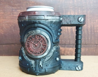Puede incluir: Una taza de estilo steampunk en negro y gris con un diseño de esfera de reloj. La taza tiene un asa y está adornada con remaches y detalles mecánicos. La esfera del reloj es roja con números romanos.
