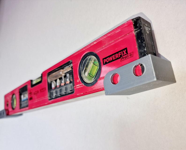 May include: A red and black level with a silver bracket. The level has a green bubble and the text "POWERFIX Profi+."