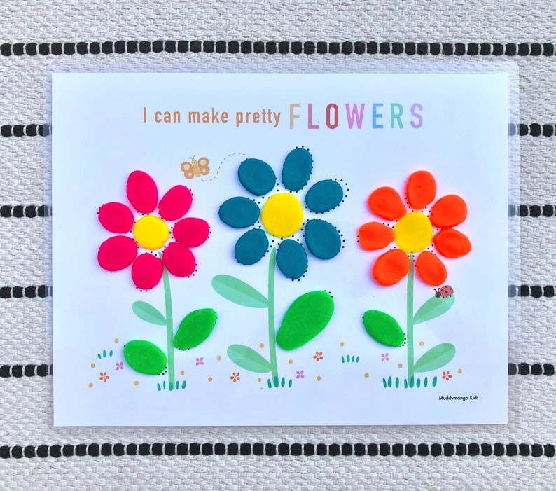 May include: A printable activity sheet with the text "I can make pretty FLOWERS" and an illustration of three flowers made from playdough. The flowers are red, blue, and orange with yellow centers. The flowers have green stems and leaves.
