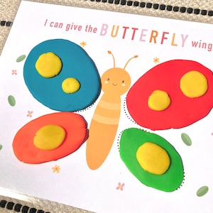 May include: A printable activity for kids to give a butterfly wings using play dough. The image shows a butterfly with a blue, red, and green wing outlines. The text "I can give the BUTTERFLY wings" is printed on the page.