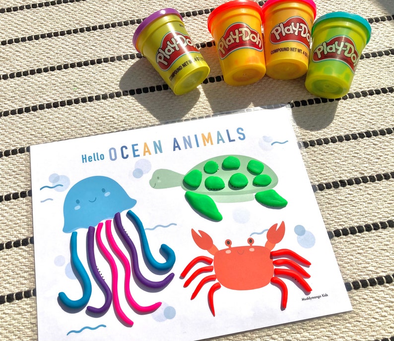 May include: A printable activity sheet with the text "Hello OCEAN ANIMALS" at the top. The sheet features a jellyfish, a turtle, and a crab. The animals are outlined and ready for children to fill in with Play-Doh.