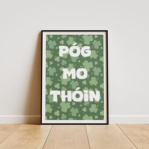 Può includere: Una stampa incorniciata con un motivo a trifoglio verde e il testo "Póg mo thóin" in bianco.