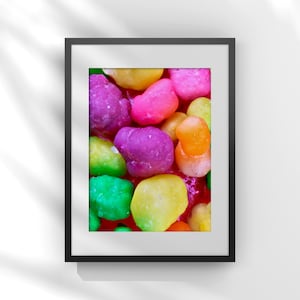 May include: A framed print featuring a close-up of colorful, candy-like objects. The objects are in various colors, including green, yellow, pink, purple, and orange. The image is set against a white background with shadows.