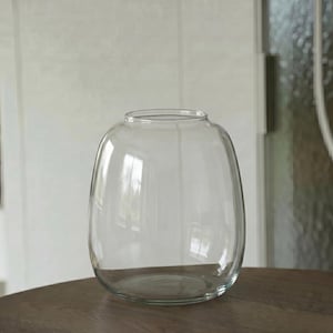 Può includere: Un vaso in vetro trasparente con un corpo arrotondato e bulboso e una stretta apertura circolare sulla parte superiore. Il recipiente presenta pareti lisce e trasparenti che consentono una visibilità completa attraverso il vetro.