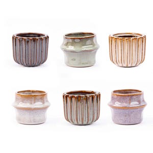 Peut inclure: Six pots en céramique de différentes couleurs et motifs. Les pots sont tous de la même taille et de la même forme, avec un fond arrondi et un haut évasé. Les pots sont émaillés dans une variété de couleurs, notamment le brun, le vert, le beige et le violet.