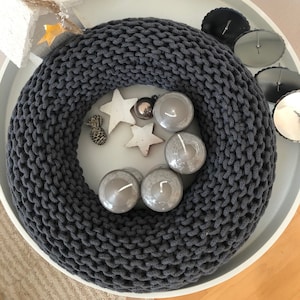 May include: A gray knitted wreath with four gray candles and white stars on a white tray.