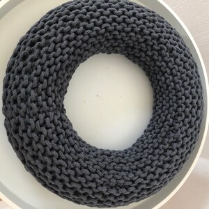 May include: A dark gray knitted wreath, perfect for a minimalist home decor style.