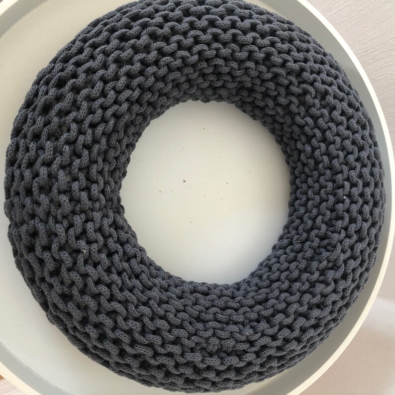 May include: A dark gray knitted wreath, perfect for a minimalist home decor style.