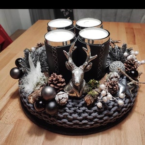 May include: A black and silver Christmas centerpiece with four candles, a deer figurine, pine cones, and white berries.